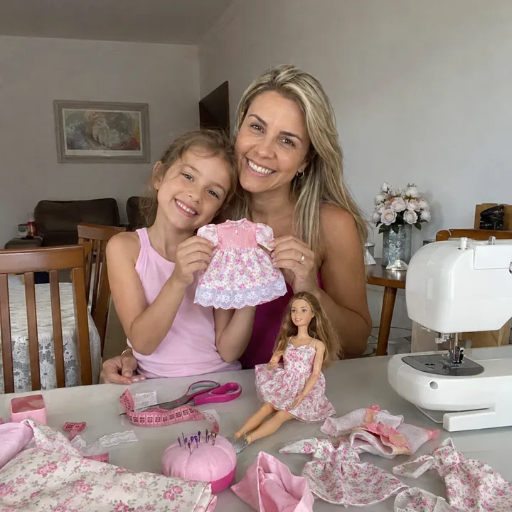 Mom and daughter sewing doll clothes at home