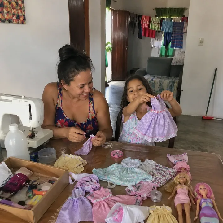 Mom watching her daughter present a doll dress sewn at home